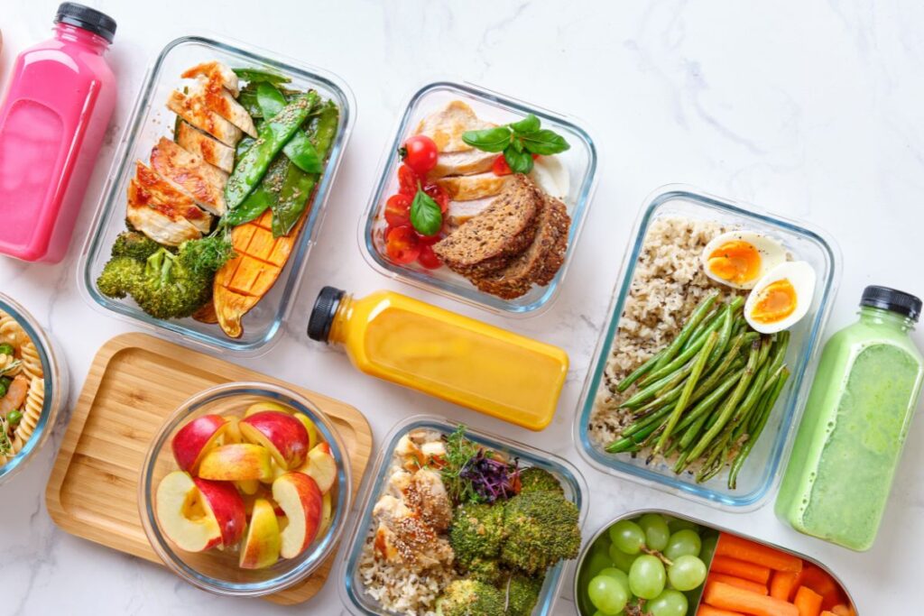 Selecionamos uma imagem simbólica para representar nutrição e fertilidade e poder escrever sobre dicas essenciais para casais. Na imagem, aparecem várias marmitas com preparações de alimentos saudáveis e alguns sucos naturais.