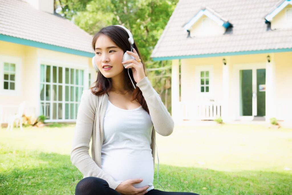 Selecionamos uma imagem simbólica para poder escrever sobre a playlist perfeita para gestantes. Na imagem, aparece uma gestante ao ar livre com fones de ouvido.